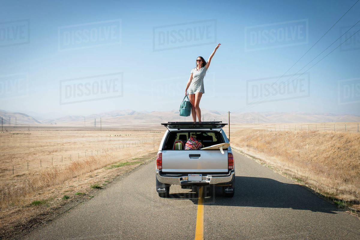Woman standing on car roof, Highway 1, California, USA Stock Photo
