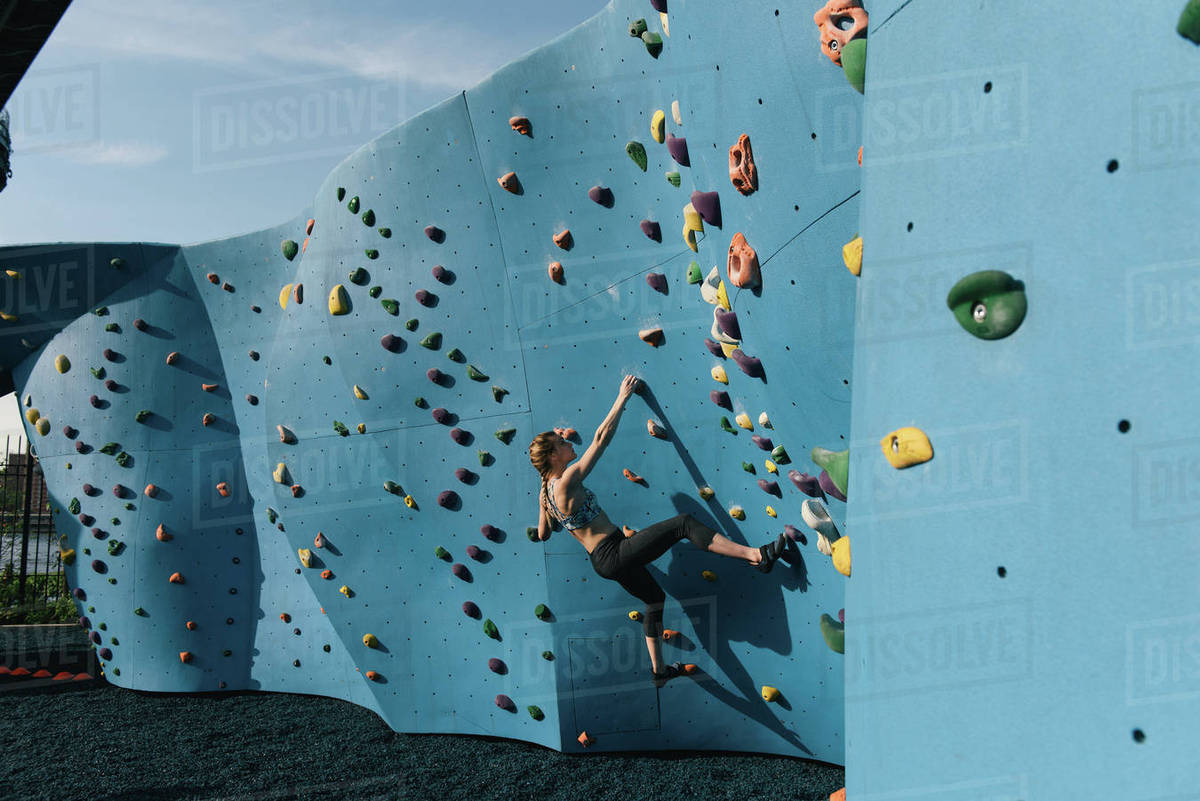 Young woman on climbing wall, Brooklyn Bridge Park, Brooklyn, New York
