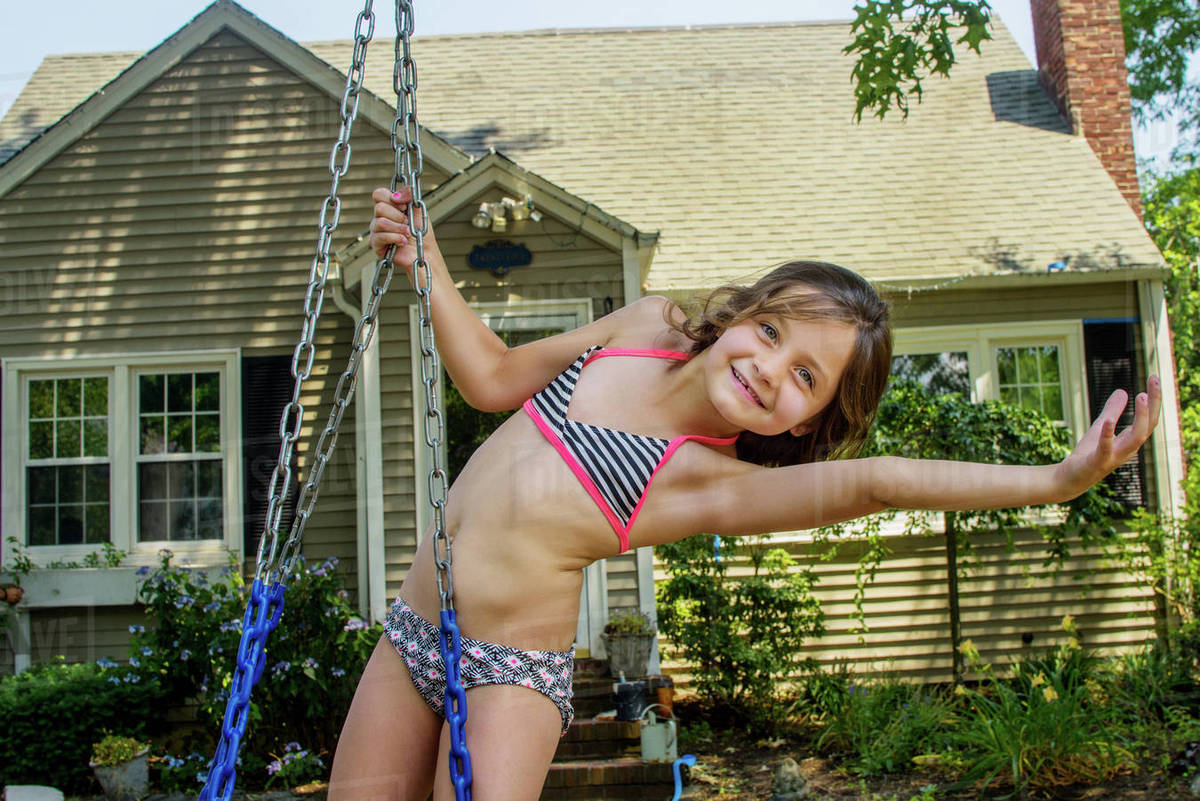 Portrait of girl bending over sideways on swing in garden Royalty-free stock photo