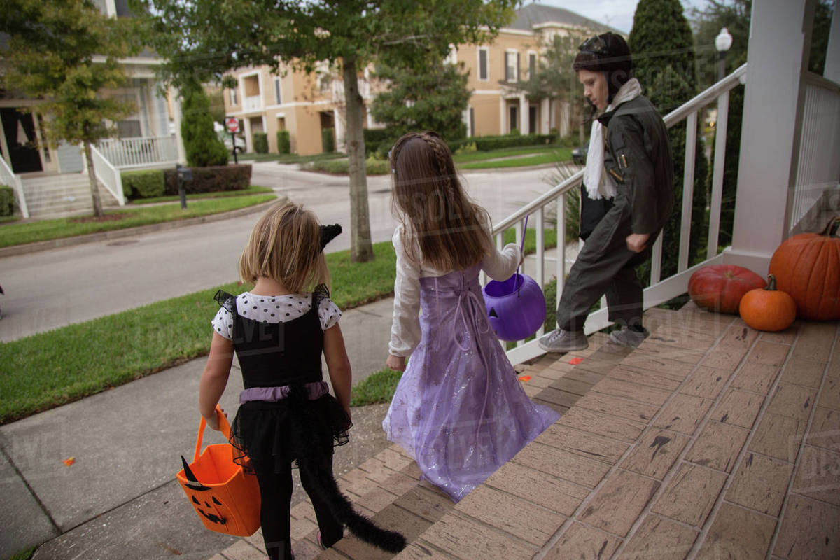 Boy and sisters trick or treating moving down porch stairway Royalty-free stock photo