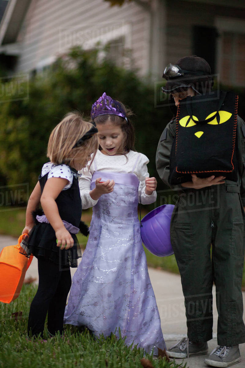 Boy and sisters trick or treating looking at treats on sidewalk Royalty-free stock photo