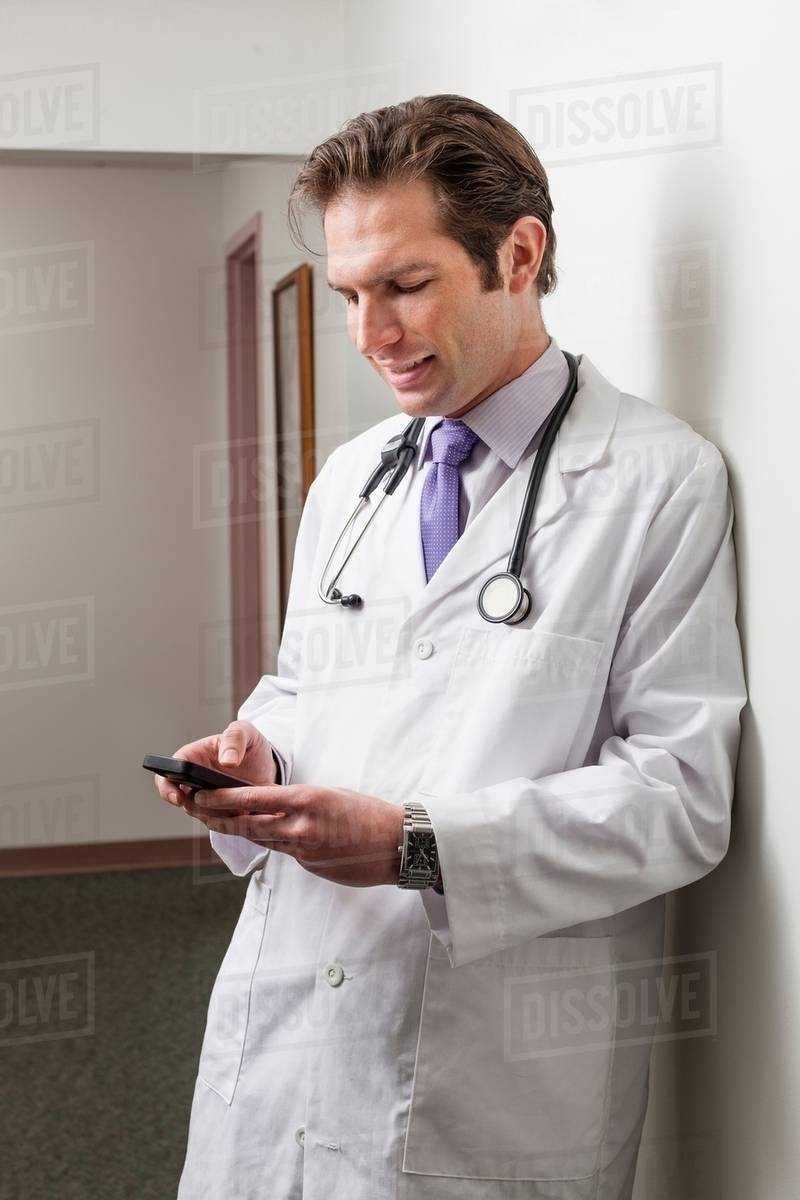 Doctor using mobile phone in hospital corridor Stock Photo Dissolve