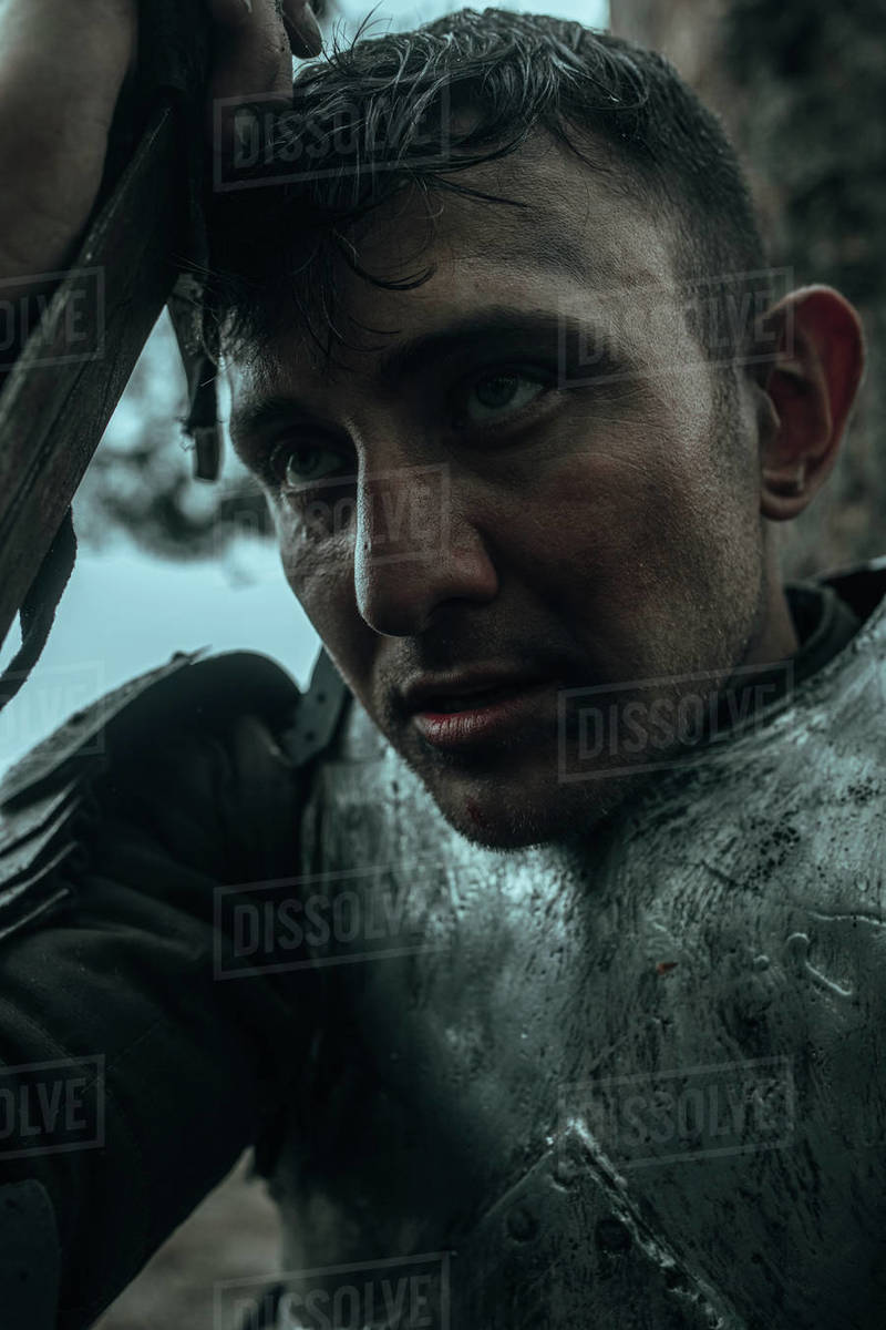 Medieval tired warrior knight in chain mail armour sits and rests among