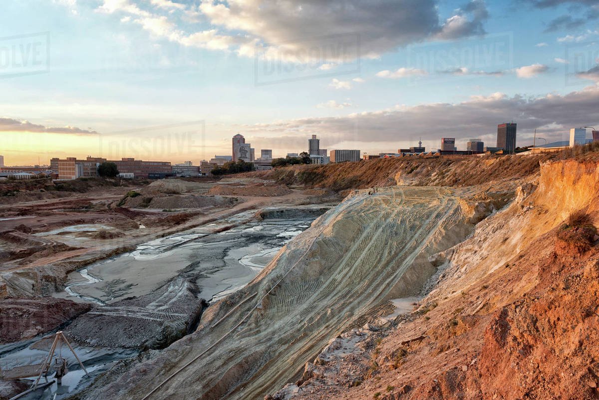 Mine dumps with Johannesburg skyline as the backdrop Stock Photo