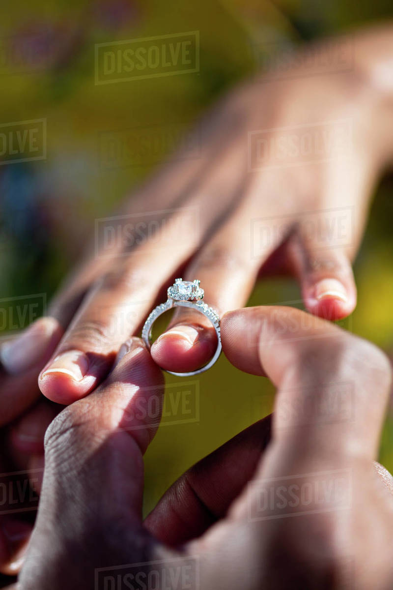 Engagement ring being put on African woman’s finger - Stock Photo