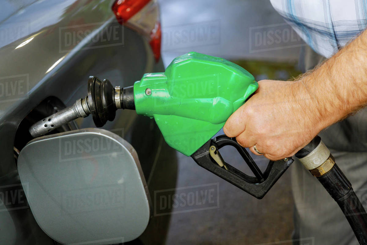 Man pumping gasoline car at gas station being filled with fuel on