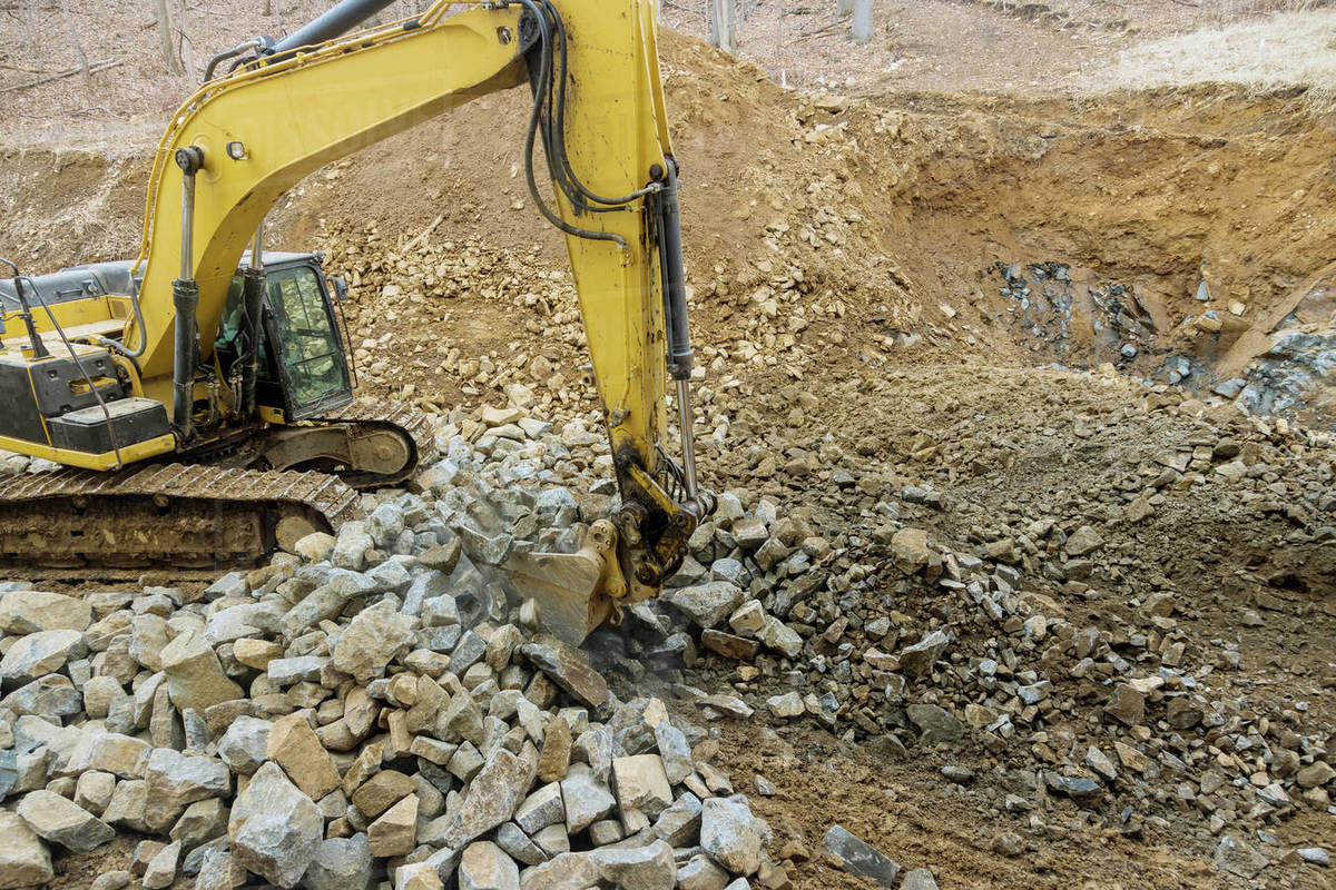 Heavy trucks with moving stone rock in a construction site on excavator ...