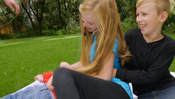 A Family Of Two Brothers And One Sister Sit On A Blanket Tickling Each Other And A Family Of Two Brothers And One Sister Sit On A Blanket Tickling Each Other And
