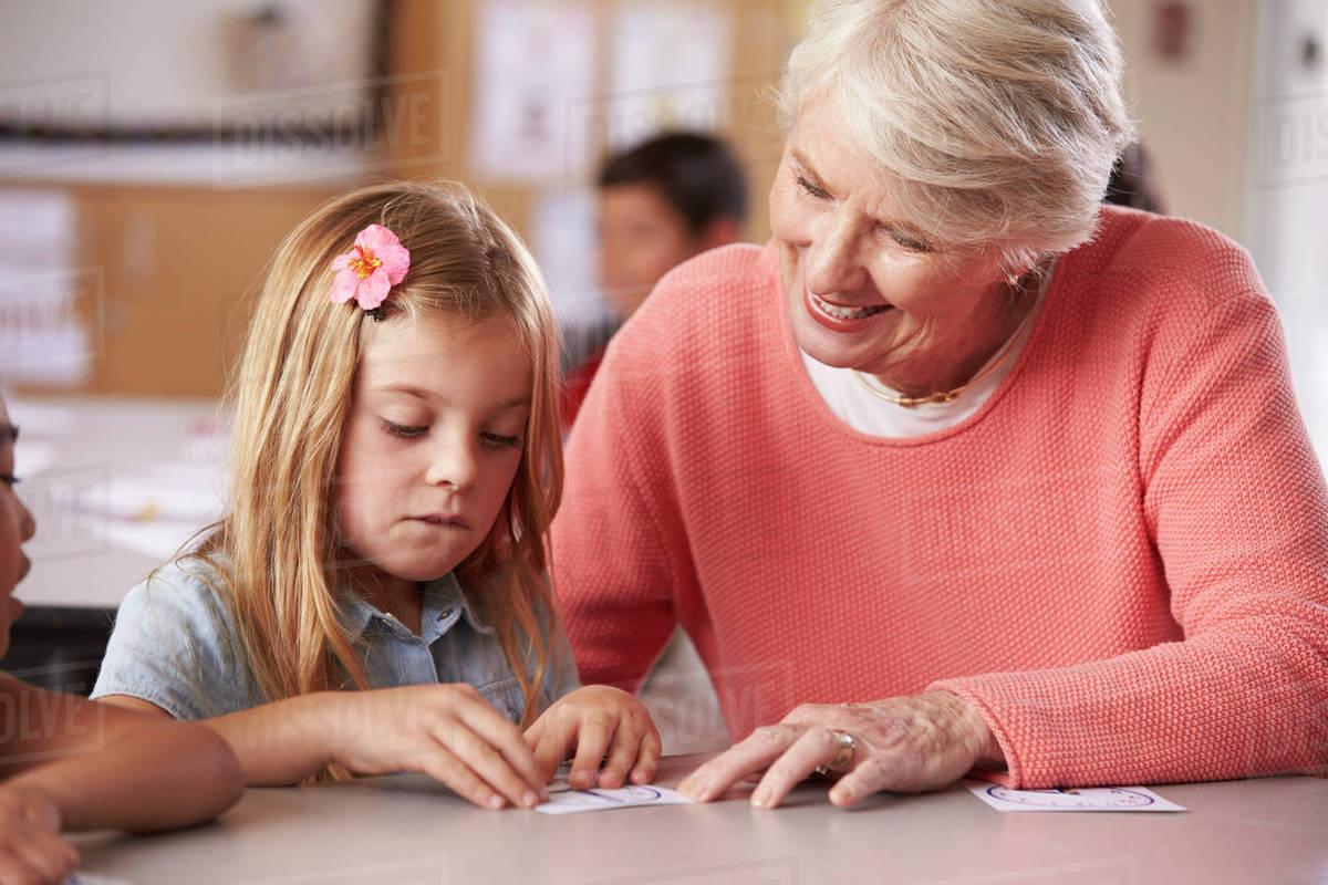 Senior Teacher Helping Schoolgirl In Elementary Class Senior Teacher Helping Schoolgirl In Elementary Class