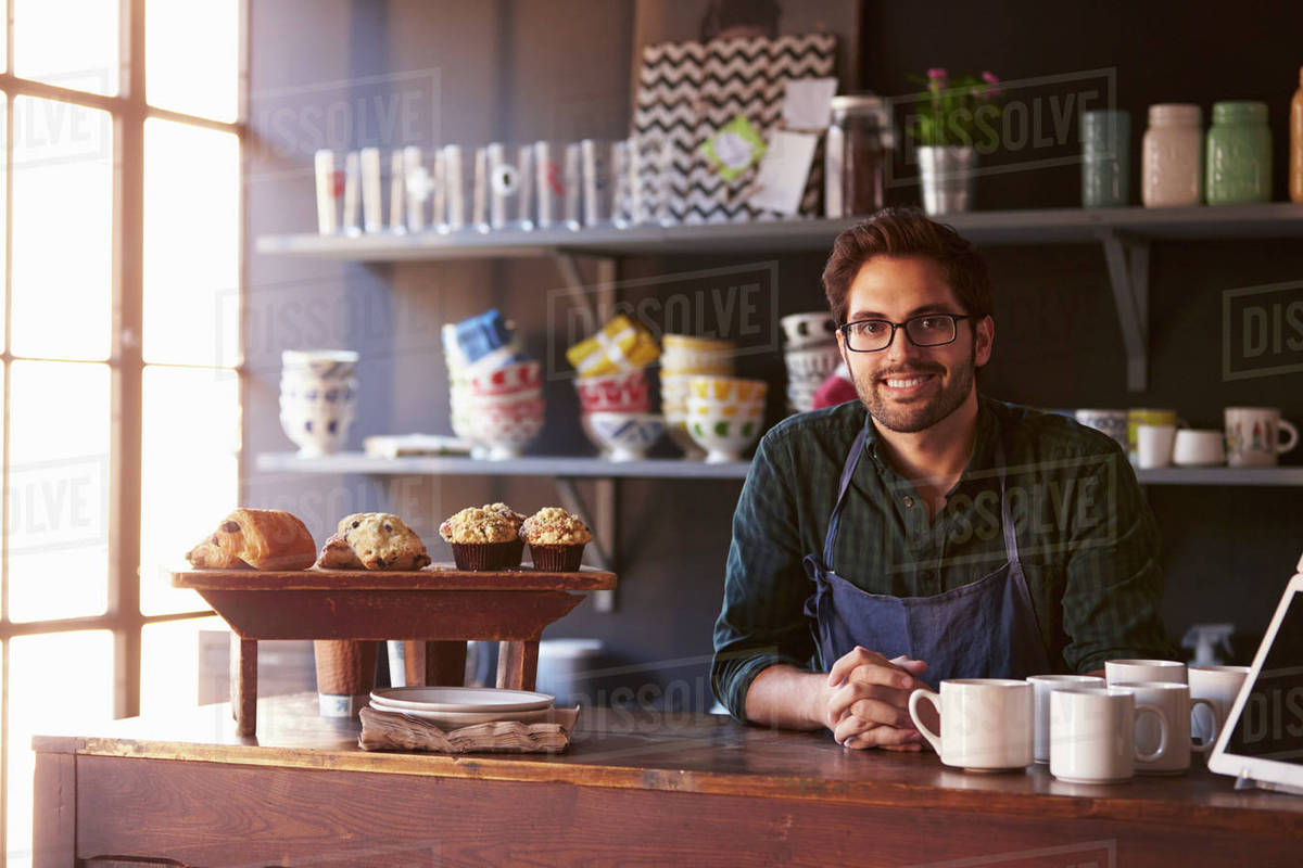Portrait Of Male Coffee Shop Owner Standing Behind Counter Stock