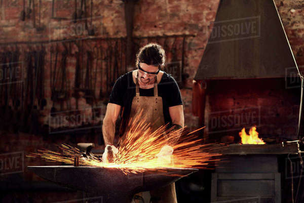 Blacksmith, man and metal workshop and sparks, manual forge working on ...