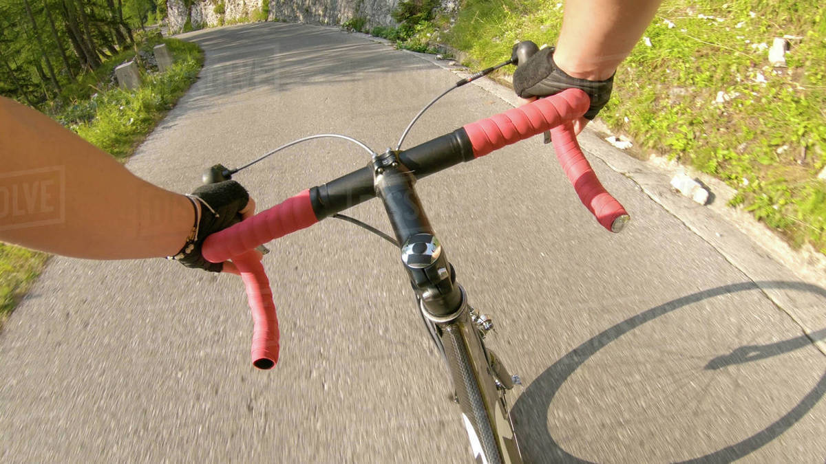 POV Male riding a road bike up a steep asphalt road running through