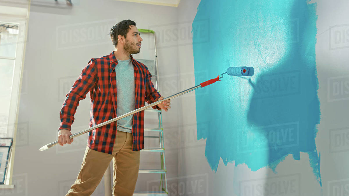 Man in Brown Jeans and Red Checked Shirt Aplies Light Blue Paint
