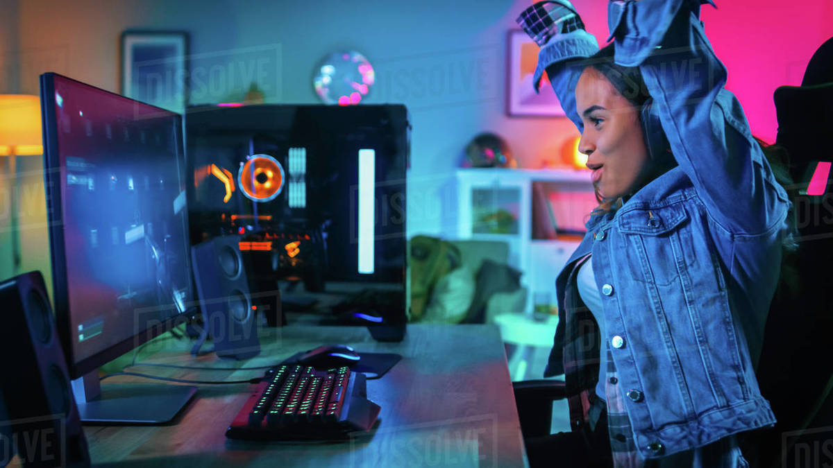 Pretty and excited black gamer girl in headphones is winning in first