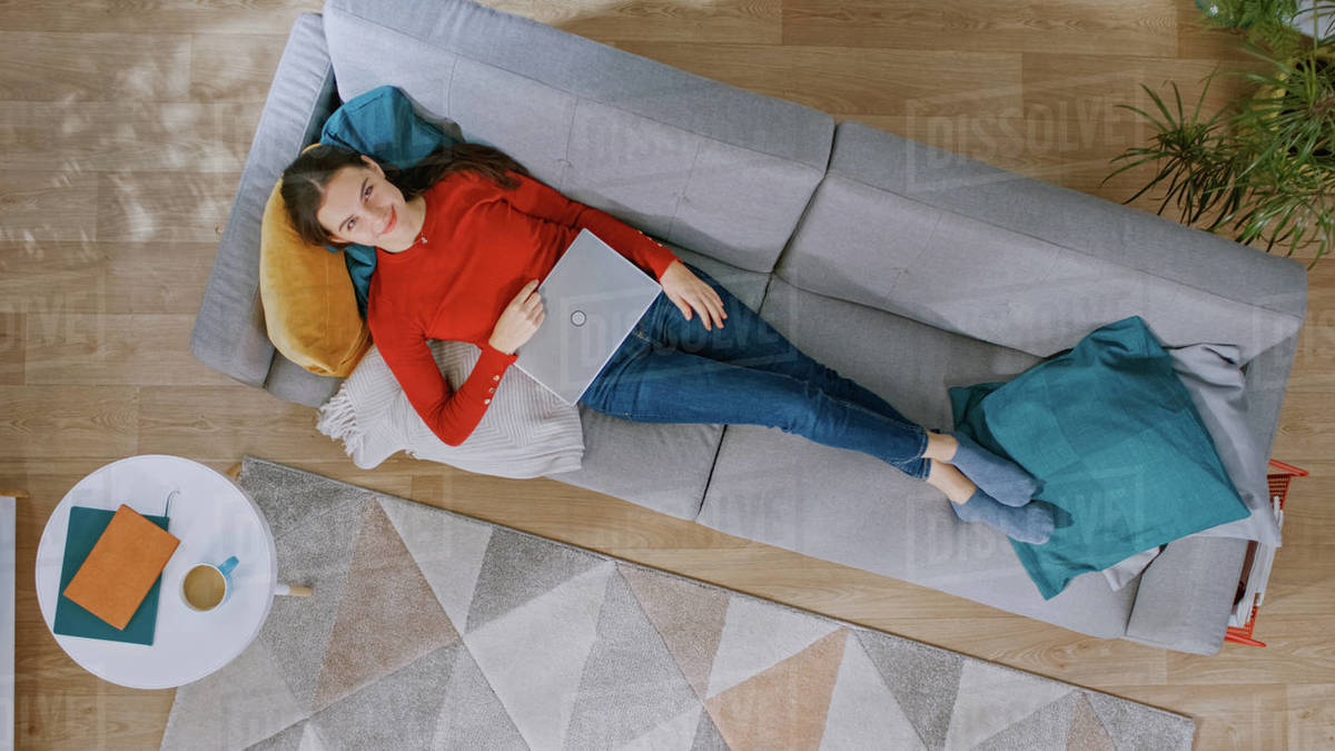 Young Girl in Red Jumper and Blue Jeans is Lying Down on a Couch