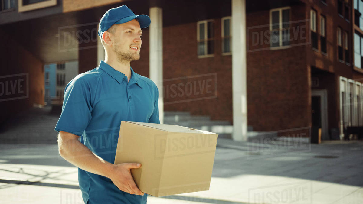 Handsome Delivery Man Holds Cardboard Box Package Walks Through Modern