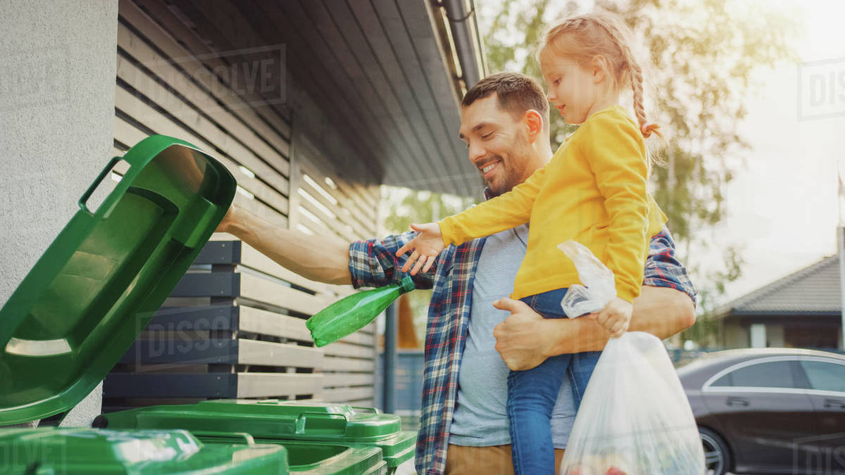 Man throwing away trash next to his house Stock Photo Dissolve