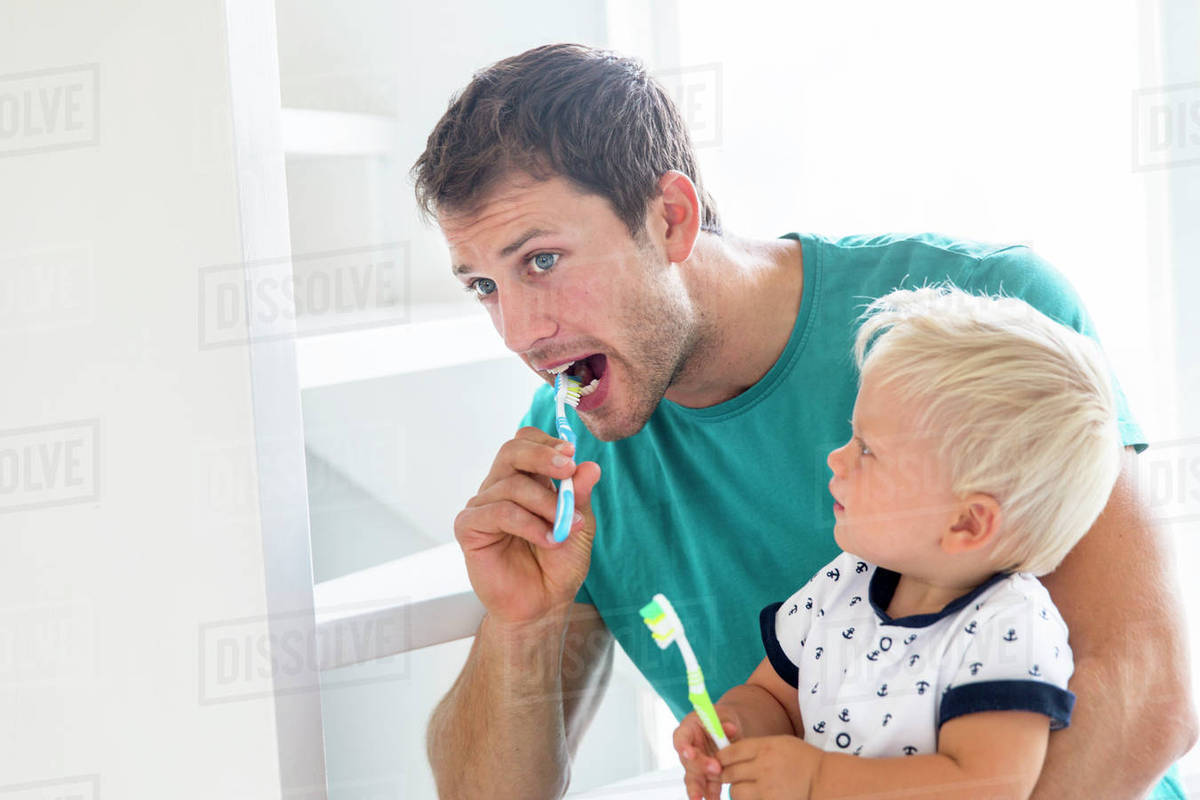 Father and son brushing teeth together Stock Photo Dissolve
