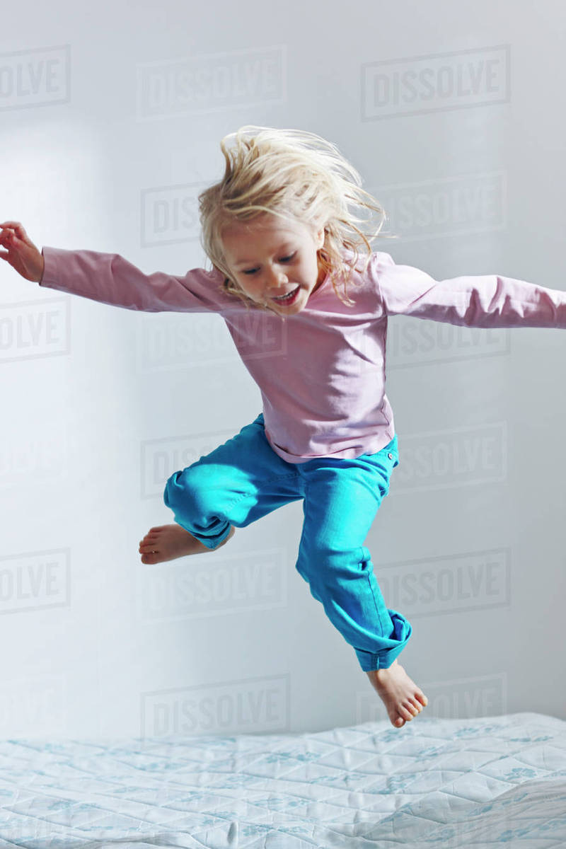 Girl jumping on bed Stock Photo Dissolve