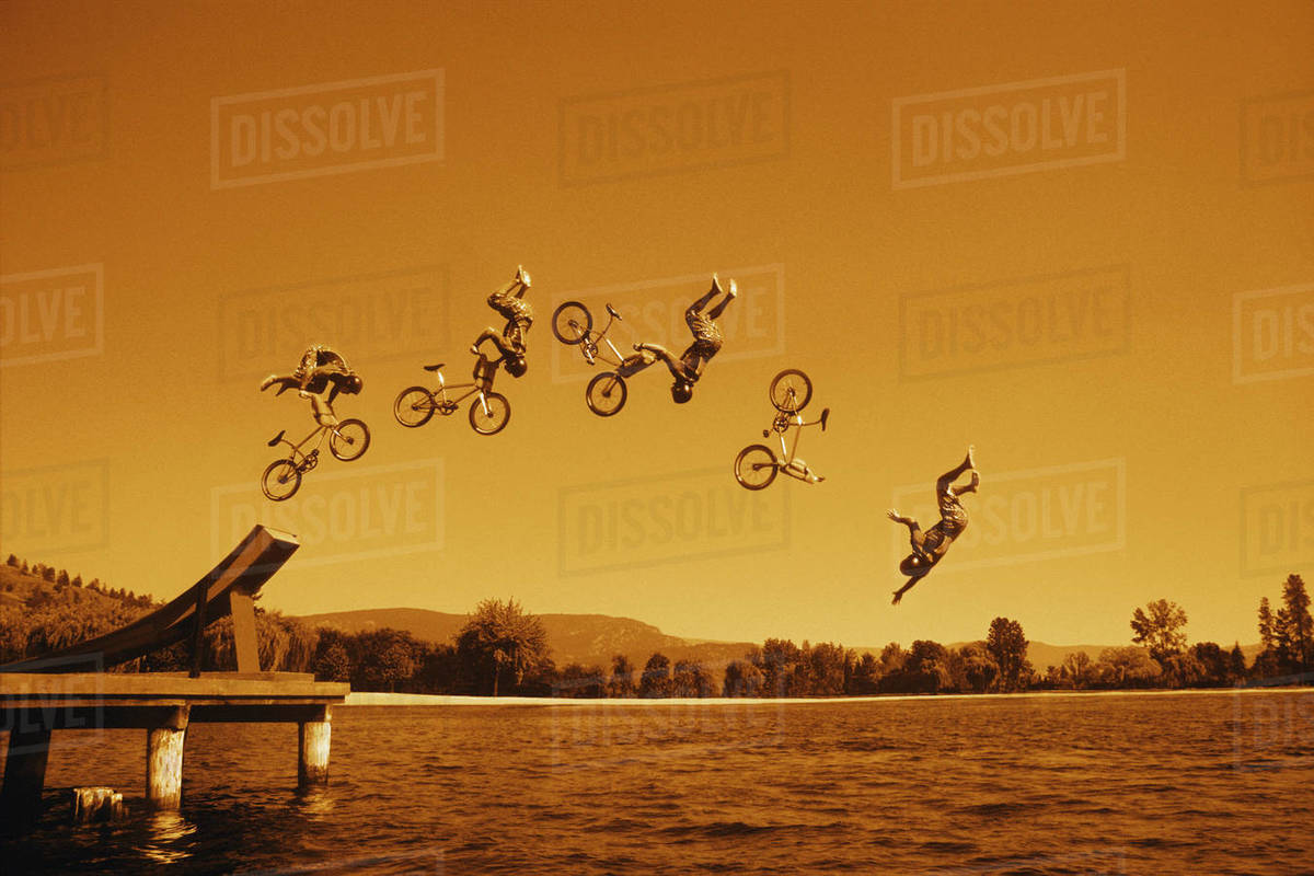Multiple Exposure Of Cyclist Going Off Jump Into Water In Brown Tones Stock Photo Dissolve