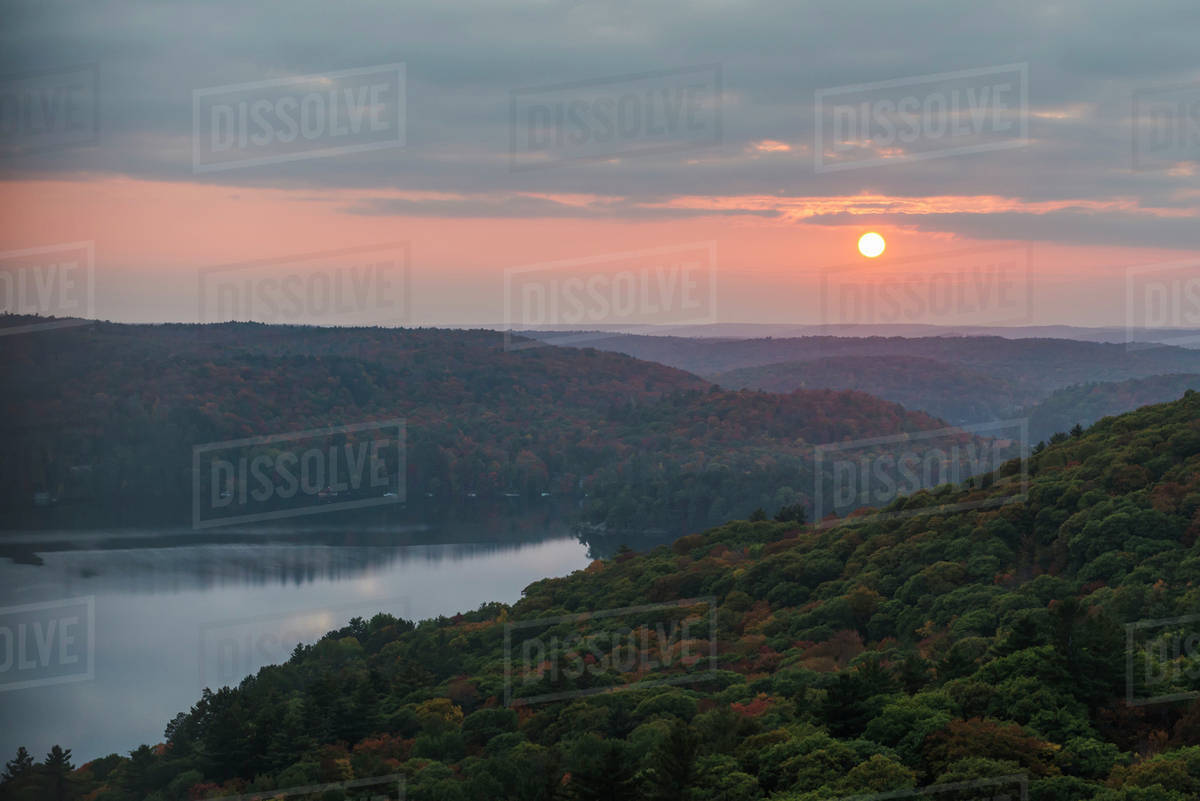 The sun setting over endless autumn coloured forests and lakes of