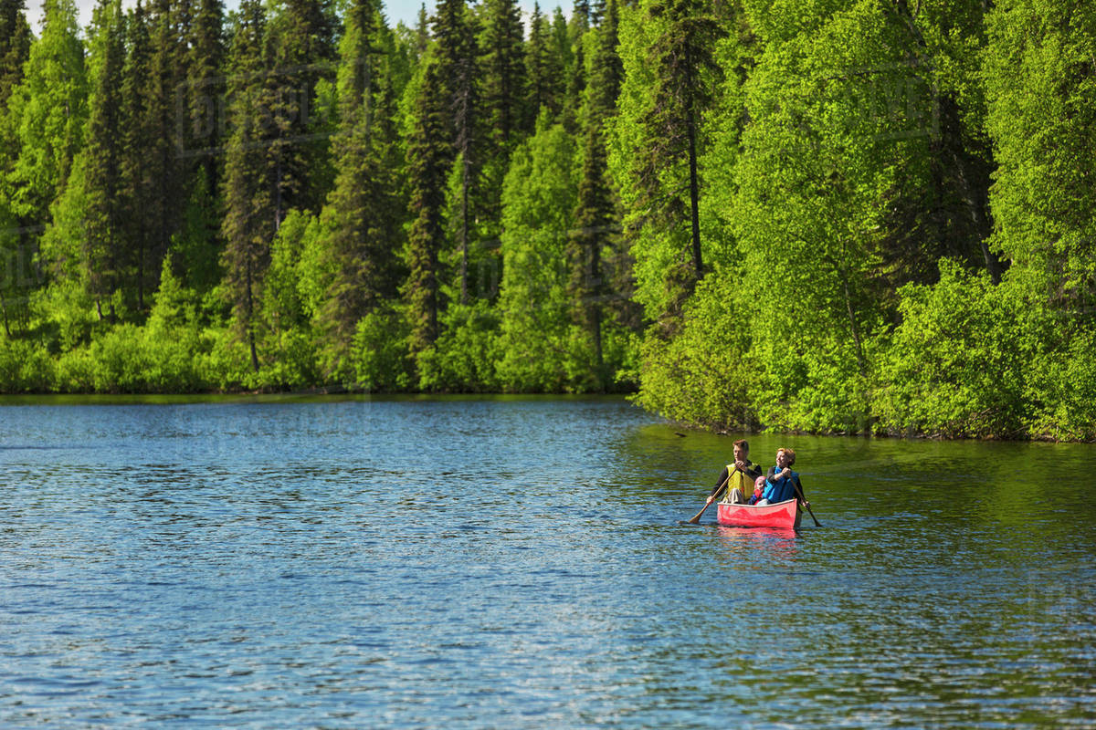 A couple and young girl in a red canoe on Byers lake with green