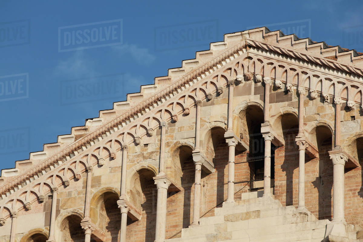 Close up of a building's roofline and romanesque architecture of columns and arches with blue sky;Parma emilia-romagna italy Royalty-free stock photo