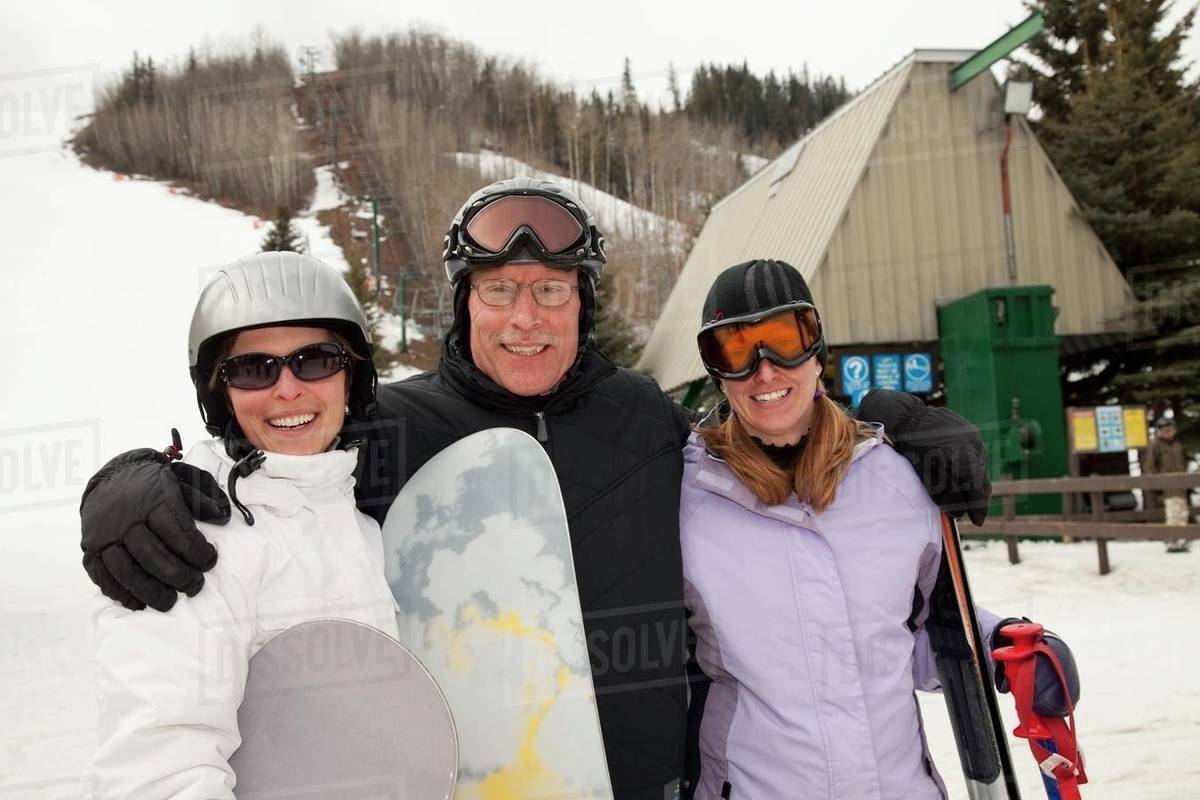 Red Deer, Alberta, Canada; Three Adults At A Ski Area Holding