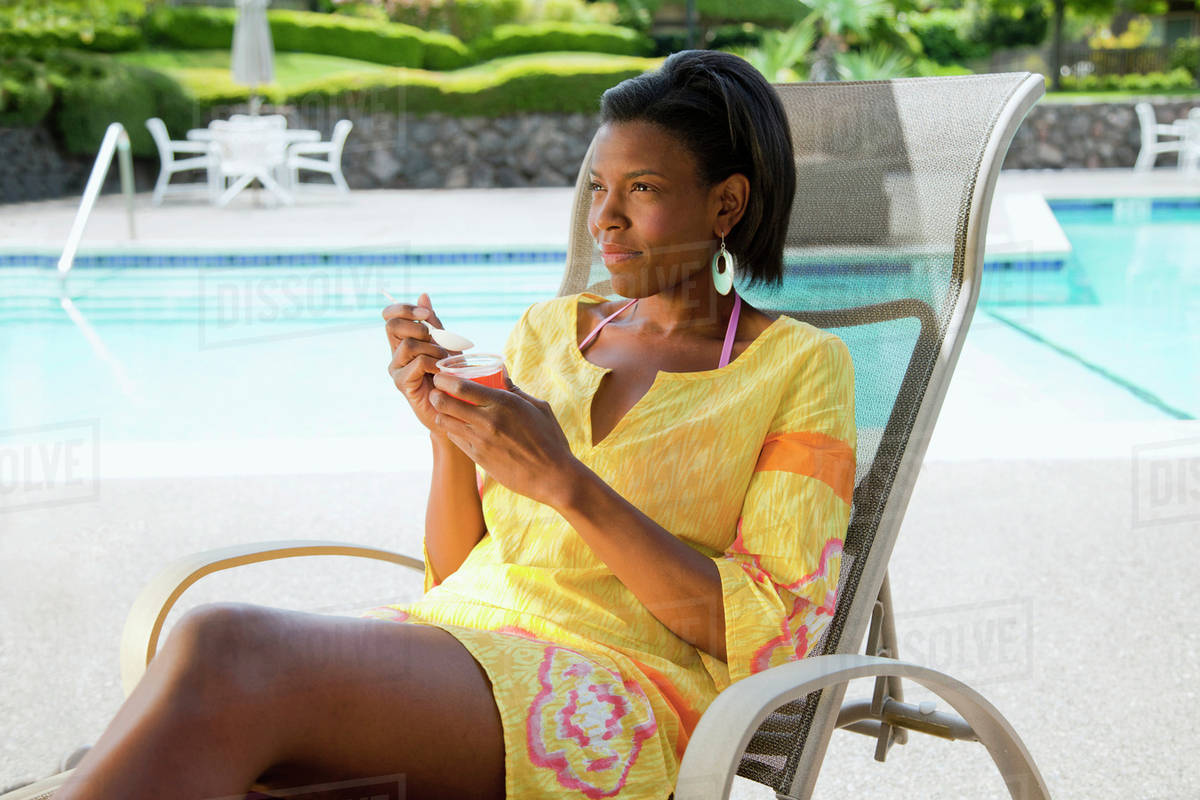 A Woman Eats A Snack Sitting In A Lounge Chair By The Pool California United States Of America Stock Photo