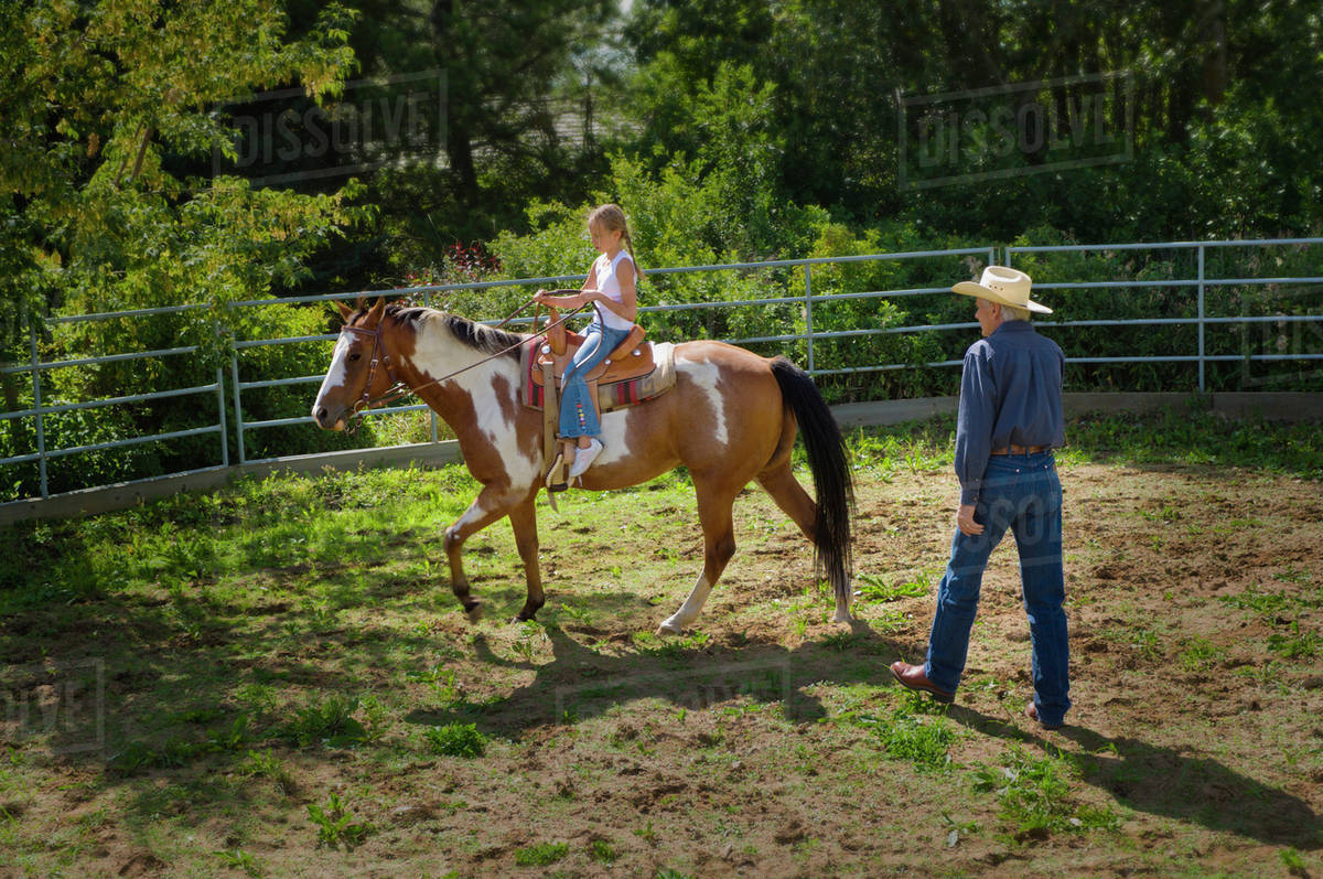 Young Girl Learning How To Ride A Horse In A Corral; Edmonton, Alberta