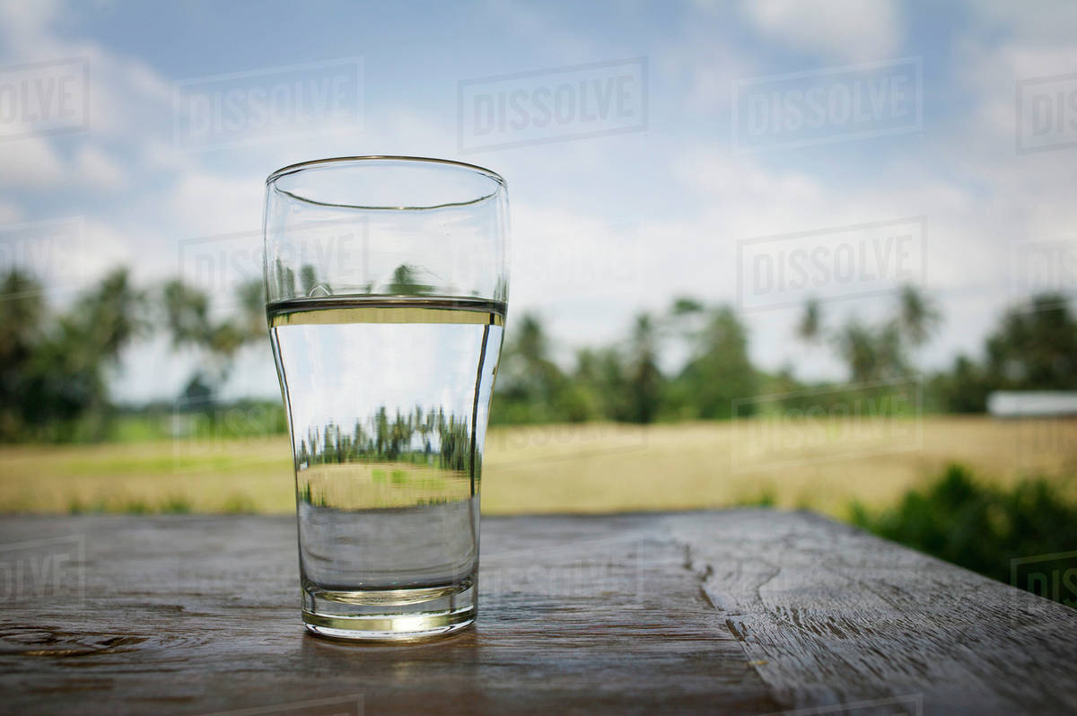 Glass Of Water On A Table With Rice Fields In The Background; Bali