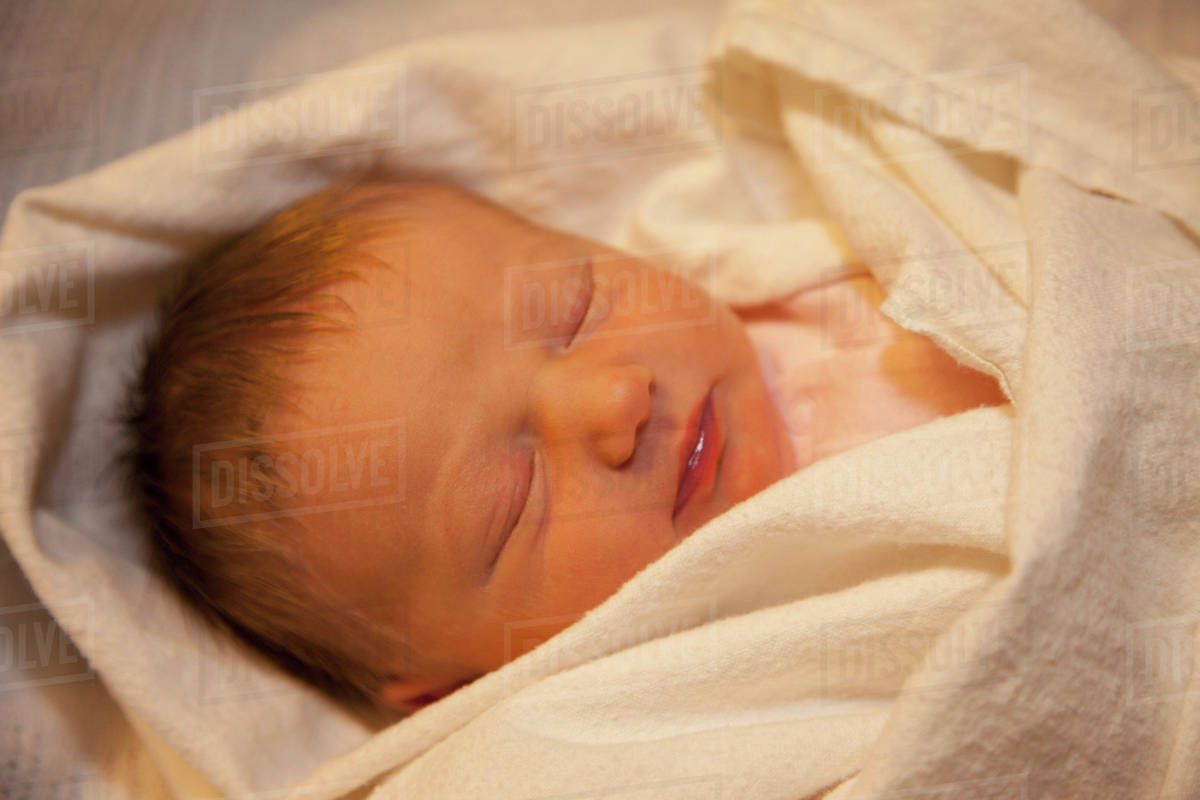 Sleeping Baby Wrapped In A White Blanket; Edmonton, Alberta, Canada Stock Photo Dissolve