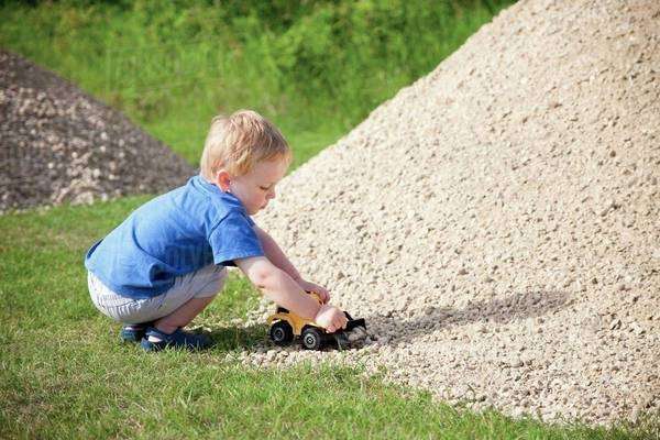 A Young Boy Drives His Toy Truck Through A Rock Pile; Edmonton, Alberta ...