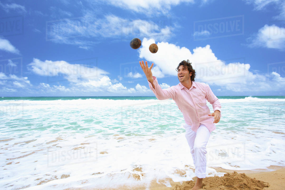 Man throwing coconuts on the beach; Kealia, Kauai, Hawaii, United