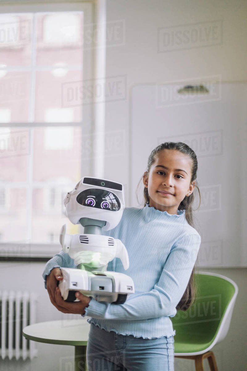 Portrait of girl carrying social robot standing in innovation lab