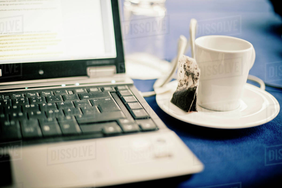Closeup of laptop and tea cup in office Stock Photo Dissolve