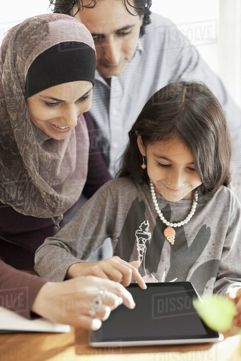 Family of three using digital tablet together at home Stock Photo Dissolve