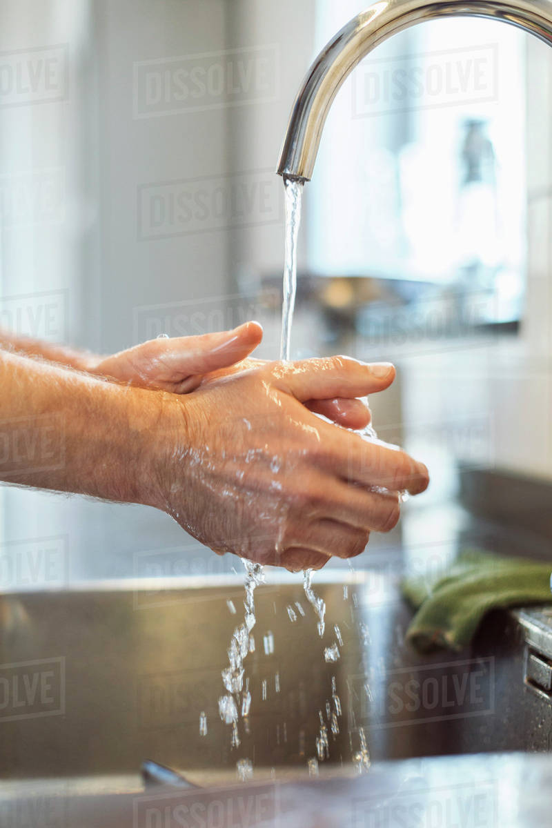 Cropped image of man washing hands in kitchen sink Royalty-free stock photo