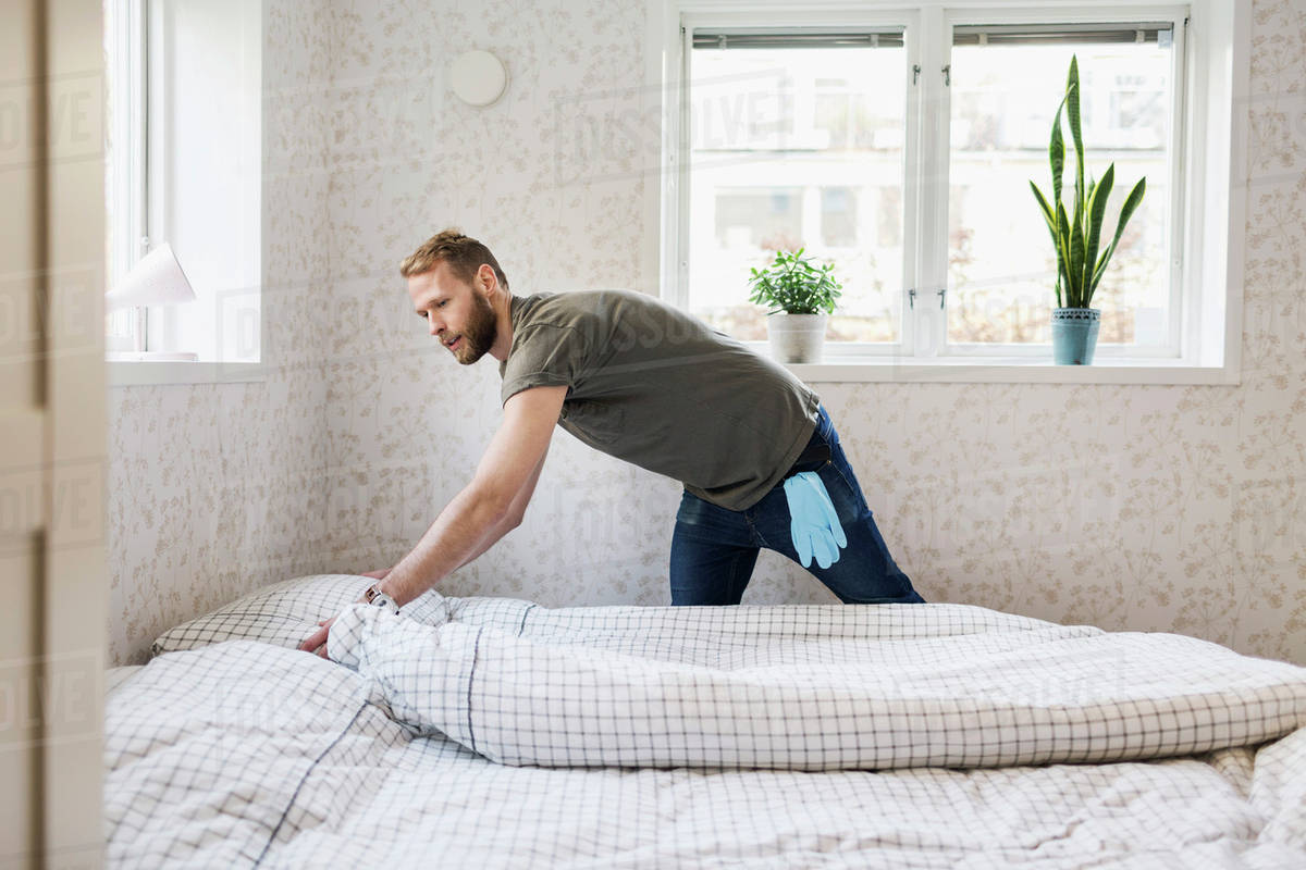 Man making bed Stock Photo Dissolve