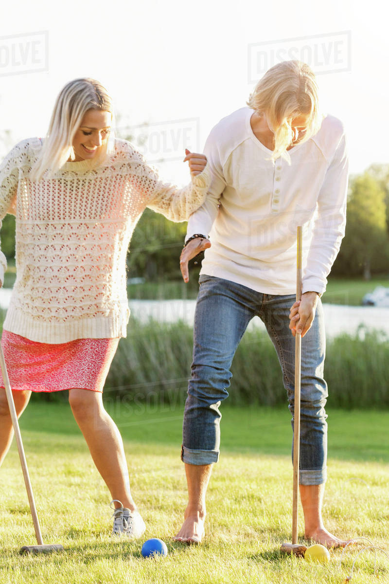 Happy friends playing croquet on field Stock Photo Dissolve