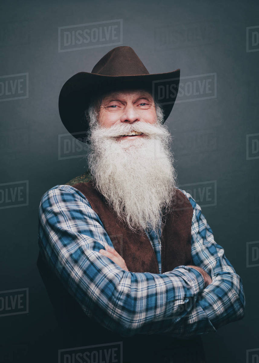 Portrait Of Happy Senior Man Wearing Cowboy Hat Against Gray