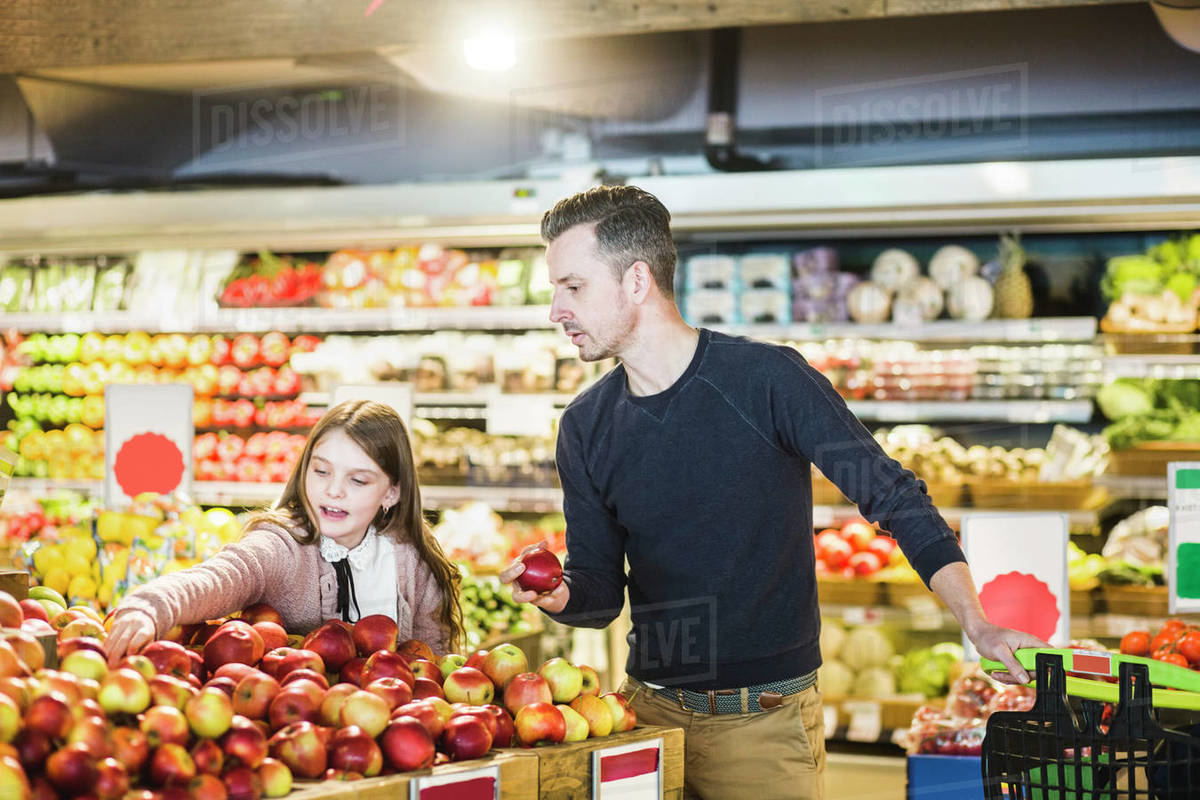 Father and daughter buying fresh apples in supermarket Stock Photo