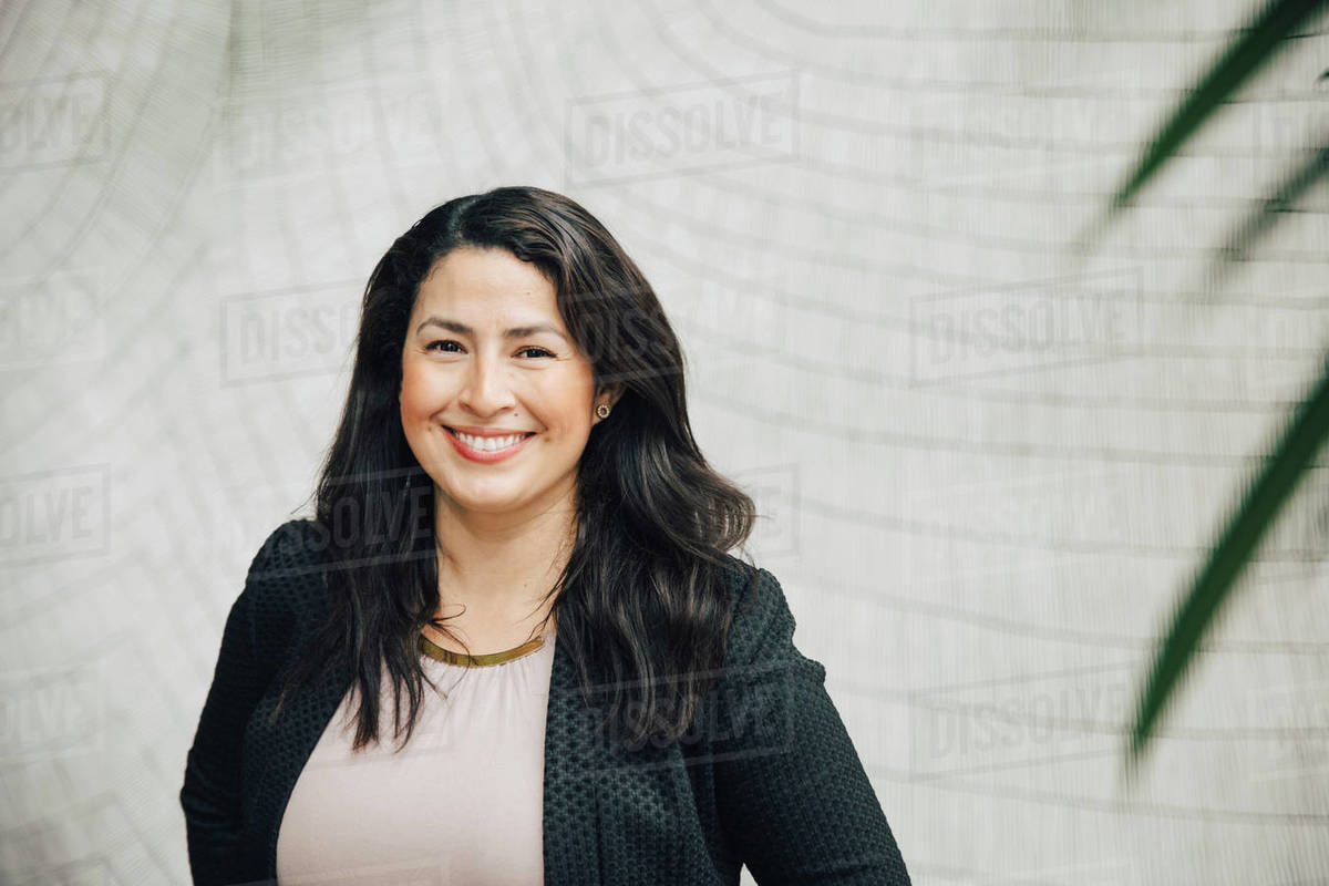 Portrait of smiling businesswoman standing against wall at office Royalty-free stock photo