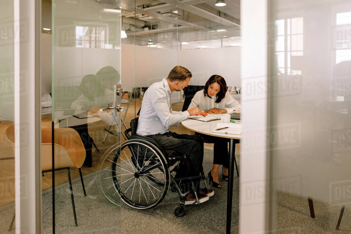 Serious female manager and disabled businessman working in board room Royalty-free stock photo