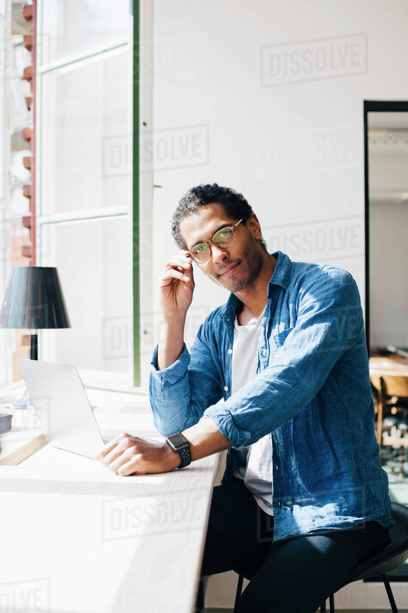Portrait of male computer programmer sitting at desk in office - Stock ...