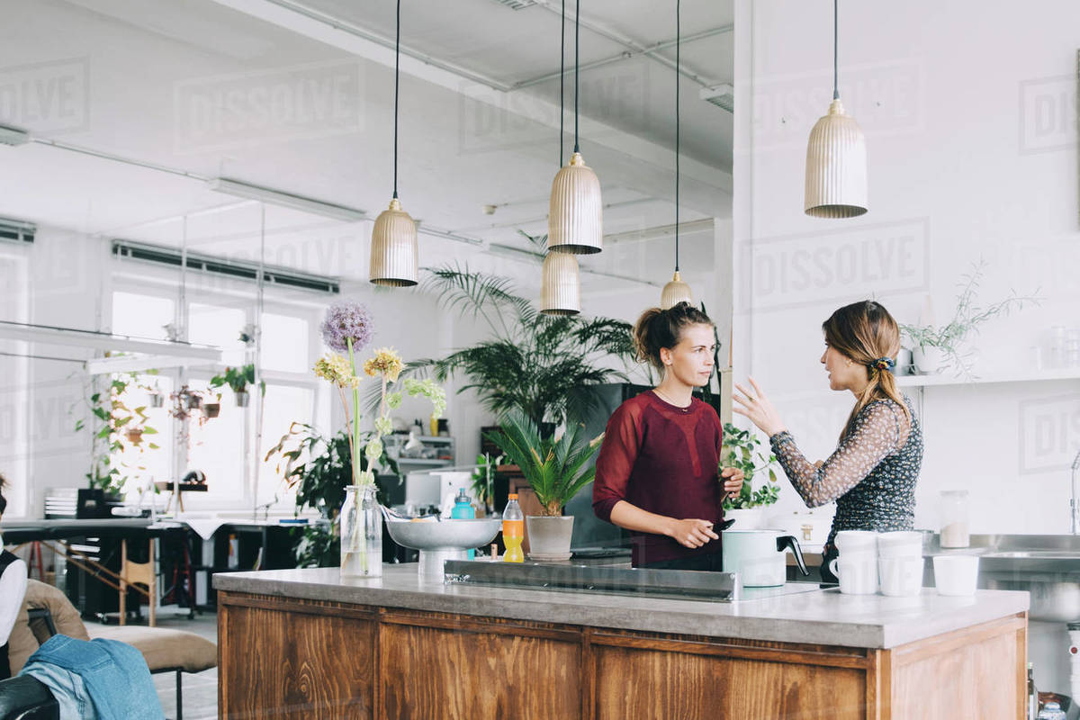 Creative businesswomen discussing at kitchen island in office Royalty-free stock photo