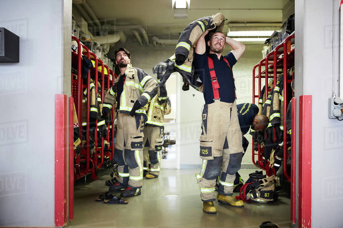 Firefighters wearing protective workwear in locker room while looking