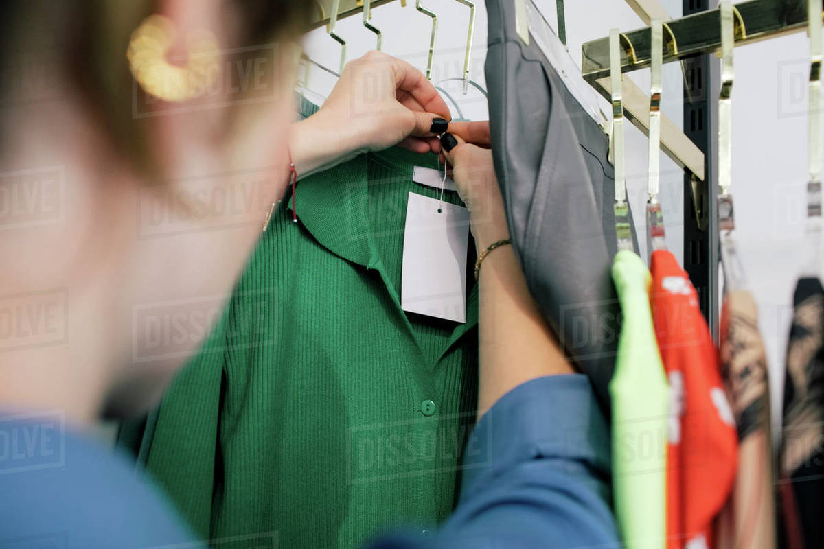 Female owner tying price tag on clothes in store Stock Photo Dissolve