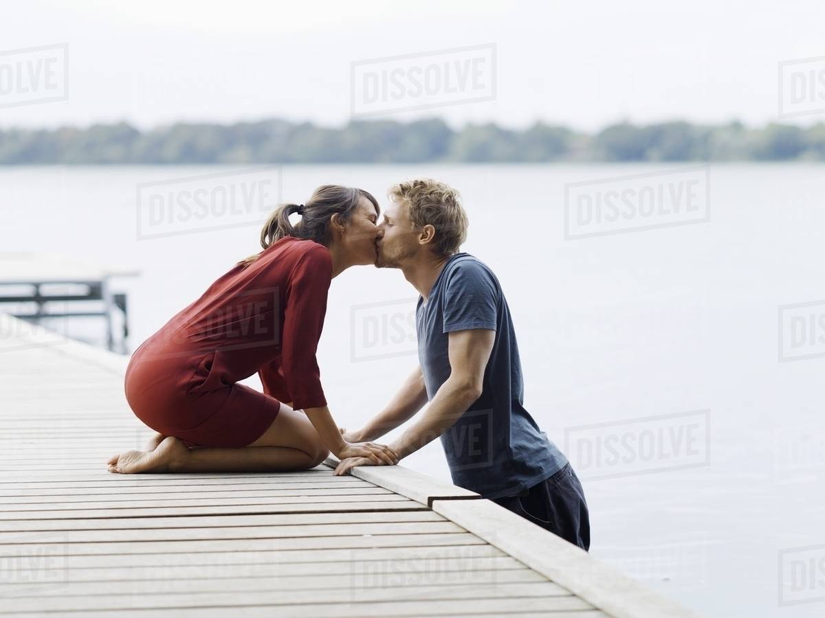 Couple on pier face to face holding hands kissing, Copenhagen, Denmark