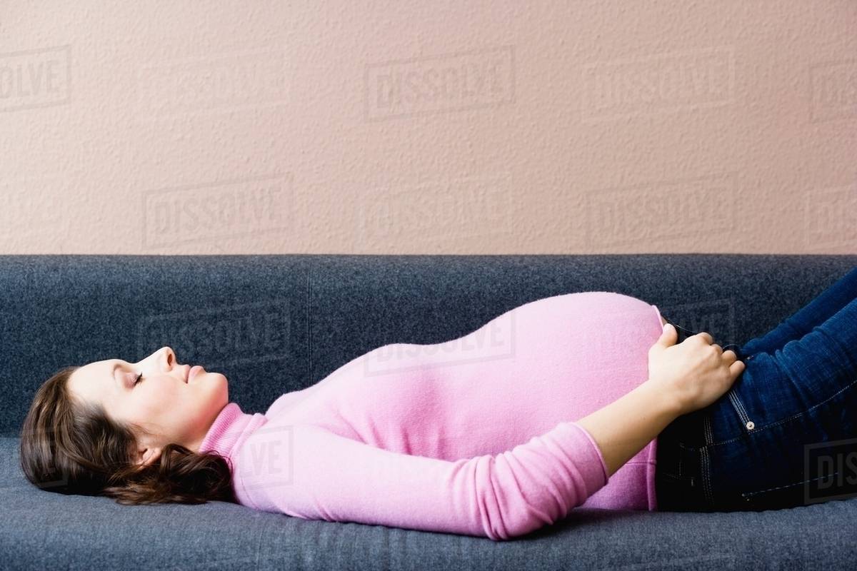 Pregnant woman laying on couch Stock Photo Dissolve